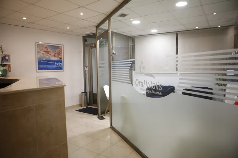 Recepción de Oral Vitalis con el logotipo de la clínica en la mampara de cristal