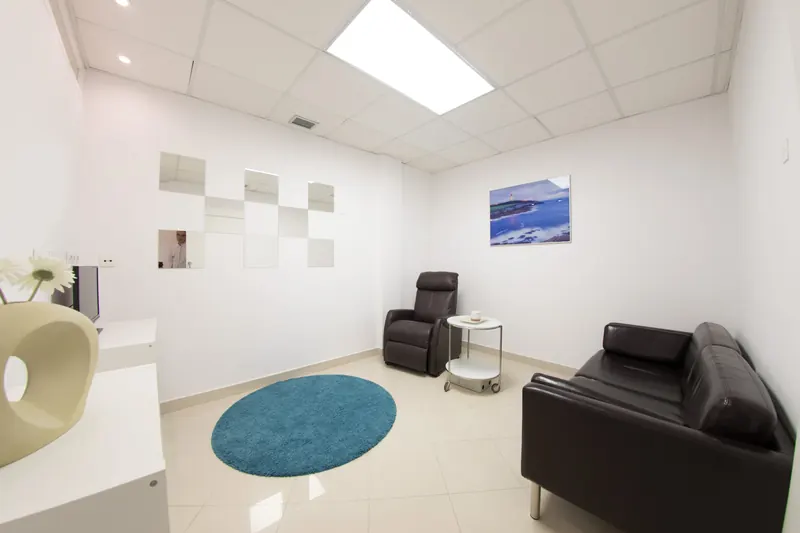 Sala posquirúrgica con sillón reclinable, sofá y alfombra azul